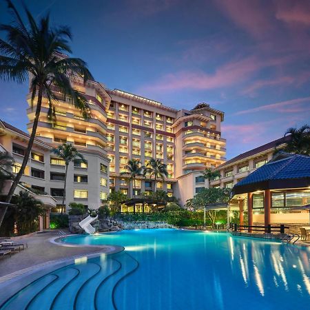 Paradox Singapore Merchant Court At Clarke Quay Exterior photo The photo shows a luxurious hotel building, featuring multiple stories and a modern architectural design. In front of the hotel, there is a large, inviting swimming pool that is illuminated in a vibrant blue hue, suggesting it may be an evening setti
