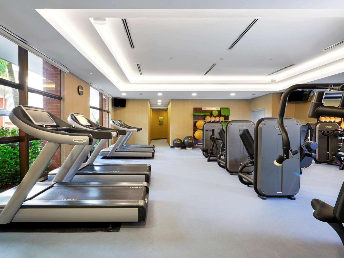 Paradox Singapore Merchant Court At Clarke Quay Exterior photo The photo shows a fitness gym interior that features several exercise machines and equipment. There are three treadmills positioned next to a large window, allowing natural light to enter the space. Alongside the treadmills, various types of strength