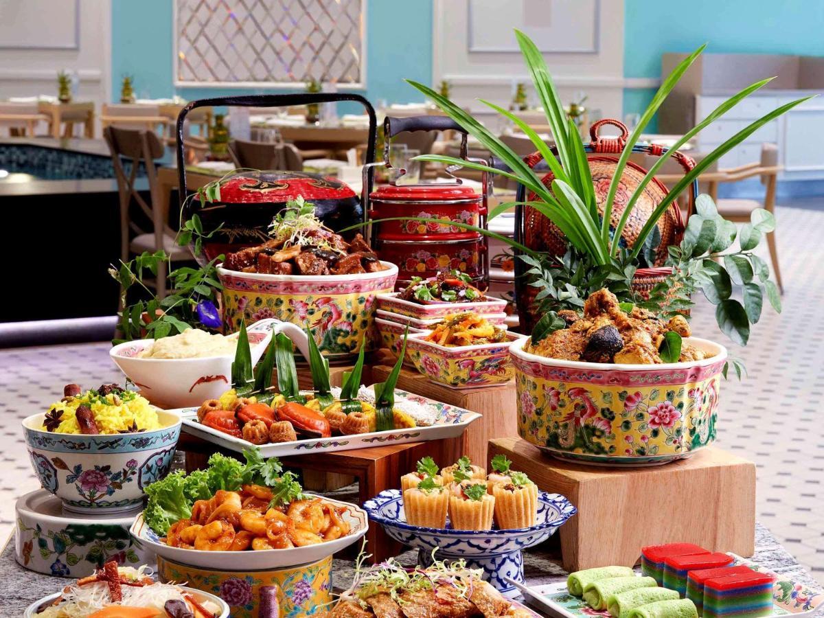 Paradox Singapore Merchant Court At Clarke Quay Exterior photo The photo displays a vibrant and lavish spread of various dishes arranged on a table. There are colorful bowls filled with different types of food, including rice, noodles, and an assortment of meats and vegetables. Some dishes are garnished with fre