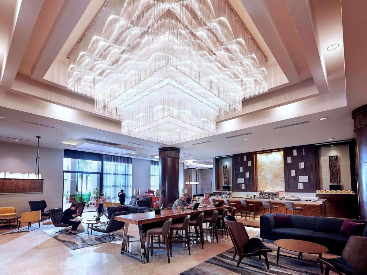 Paradox Singapore Merchant Court At Clarke Quay Exterior photo The photo depicts a modern, stylish lobby area. It features a striking chandelier that hangs from a high ceiling, creating a focal point above the seating areas. The furnishings include a mix of chairs and tables, with a cozy ambiance provided by var
