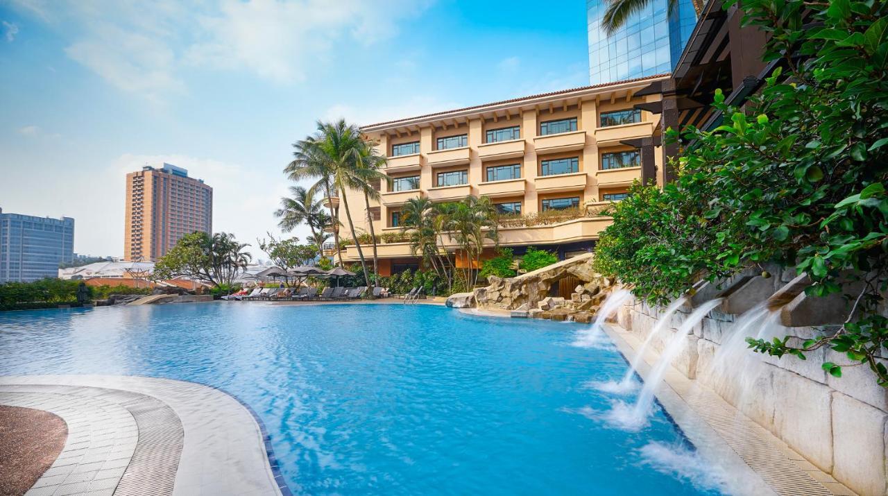 Paradox Singapore Merchant Court At Clarke Quay Exterior photo The photo showcases a scenic hotel resort with a large blue swimming pool in the foreground. The pool features artificial rock formations and small waterfalls cascading gently into the water. Surrounding the pool are lush tropical plants and palm tre