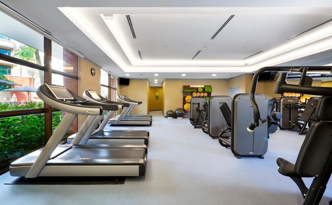 Paradox Singapore Merchant Court At Clarke Quay Exterior photo The photo depicts an indoor gym or fitness area. There are several modern treadmills lined up against one wall, with large windows allowing natural light to enter. The gym features various fitness machines arranged throughout the space, including str