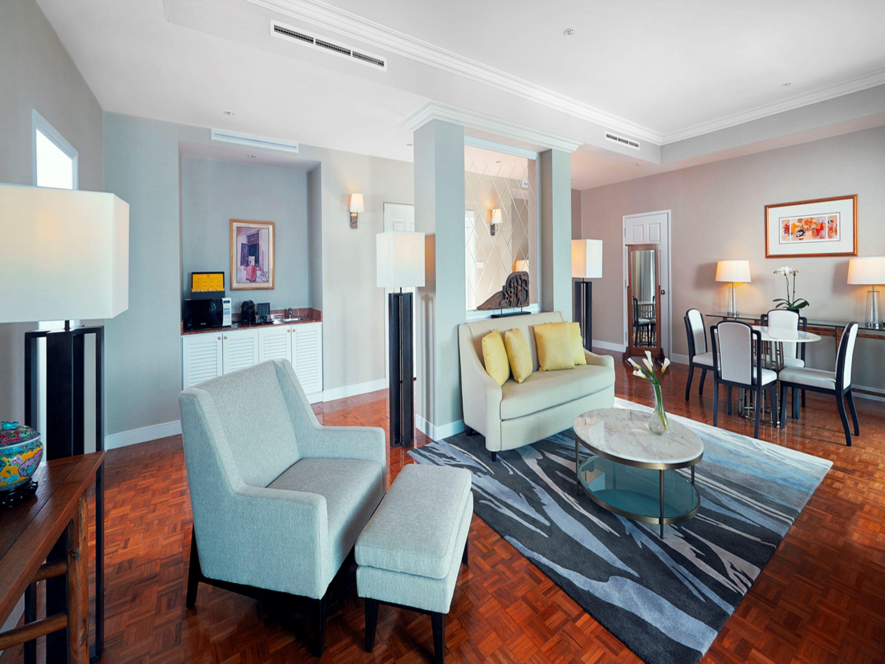 Paradox Singapore Merchant Court At Clarke Quay Exterior photo The photo shows a modern and stylish living space. It features a pair of light-colored armchairs and a settee with yellow cushions, arranged around a circular glass coffee table. A patterned area rug lies underneath. There are floor lamps providing l