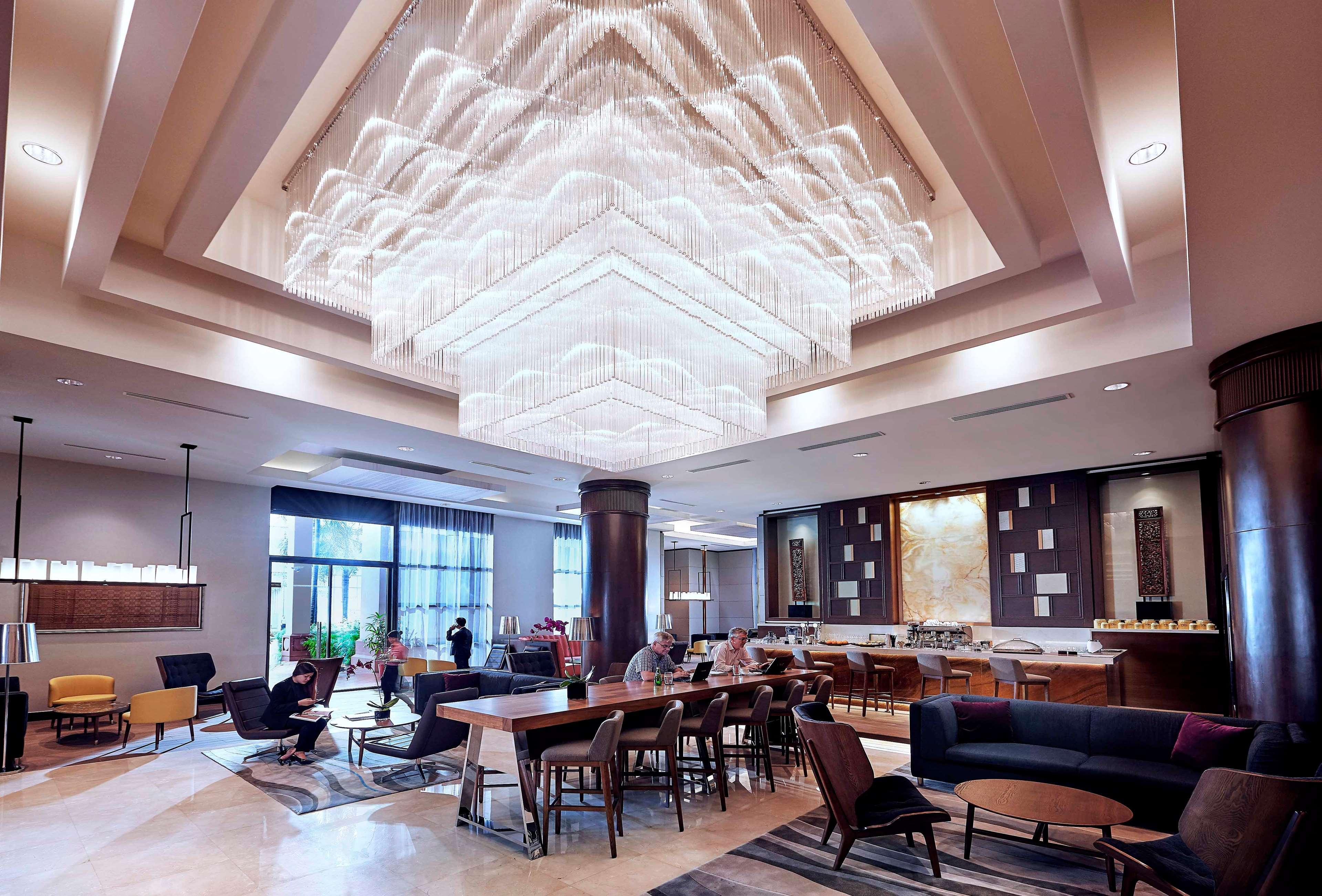 Paradox Singapore Merchant Court At Clarke Quay Exterior photo The photo shows a modern and stylish interior space, likely a hotel lobby or lounge. A large, intricate chandelier hangs from the ceiling, illuminating the area with soft light. The floor is composed of elegant tiles, and there is a mix of seating ar