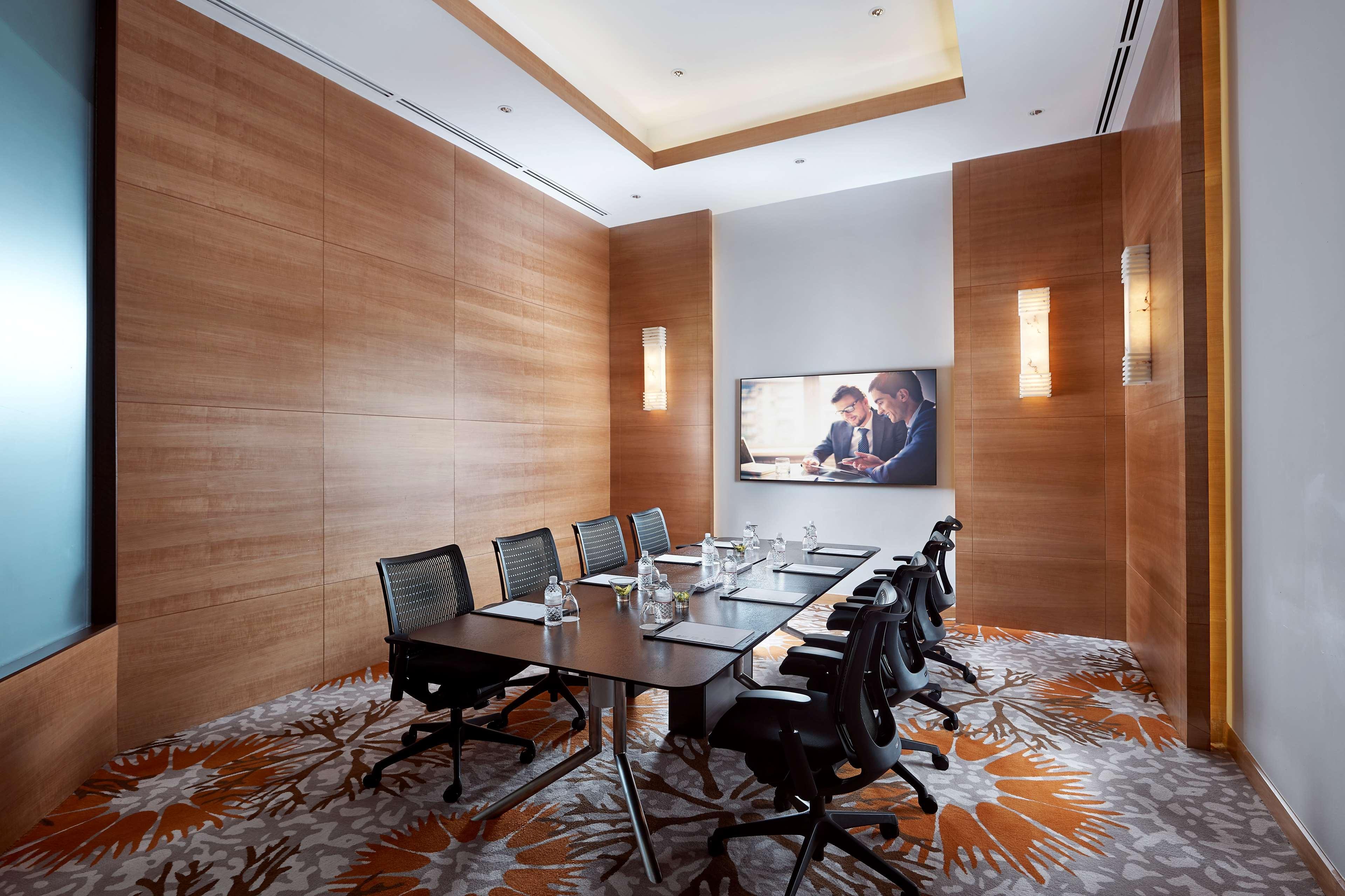 Paradox Singapore Merchant Court At Clarke Quay Exterior photo The photo shows a modern conference room featuring a large wooden table surrounded by several black office chairs. The room has wooden paneling on the walls, creating a warm ambiance. There's a large screen mounted on one wall, likely for presentatio