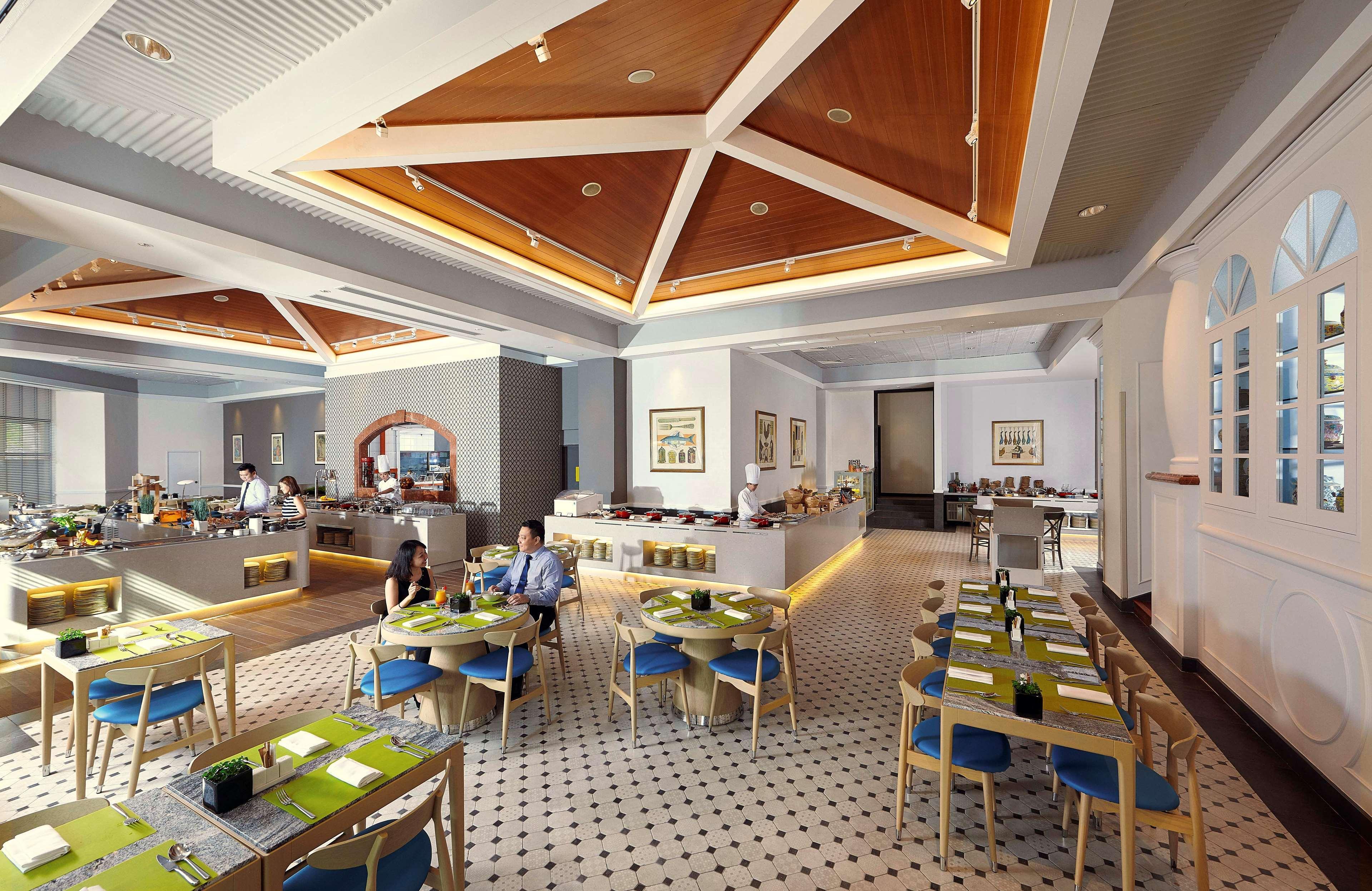 Paradox Singapore Merchant Court At Clarke Quay Exterior photo The photo shows a modern restaurant interior with a spacious layout. The ceiling features a geometric wooden design, adding a touch of elegance. The floor has a checkered pattern, contributing to the decor's stylish feel. 

There are several tables a