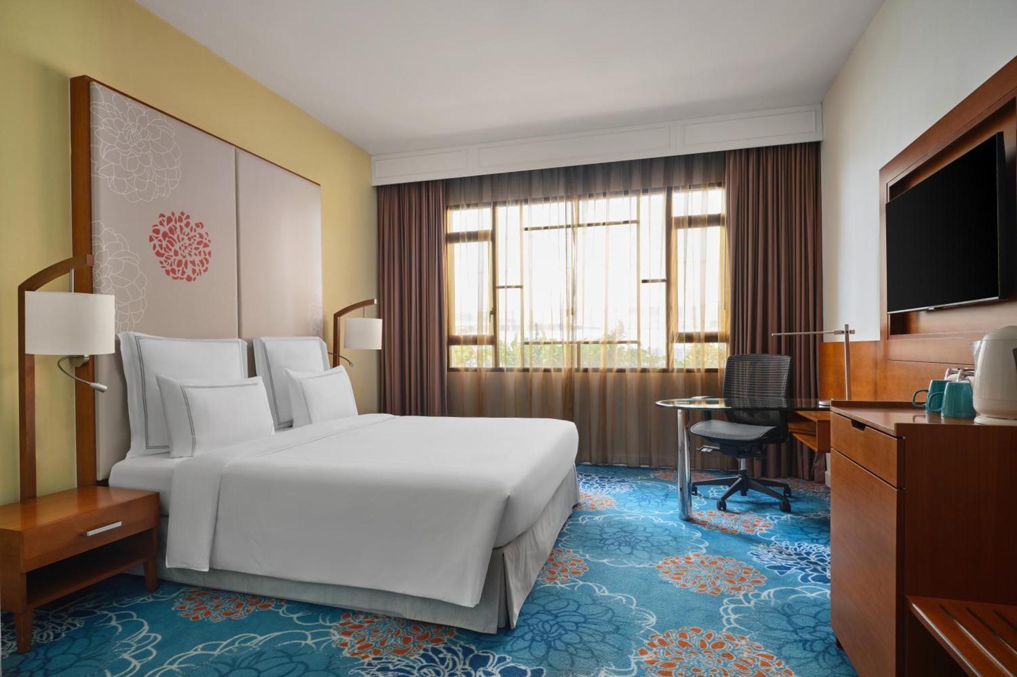 Paradox Singapore Merchant Court At Clarke Quay Exterior photo The photo shows a hotel room featuring a modern and inviting design. It includes a bed with white linens, two bedside lamps, and a decorative wall behind the bed. There is a large window covered with sheer and dark curtains, allowing natural light to