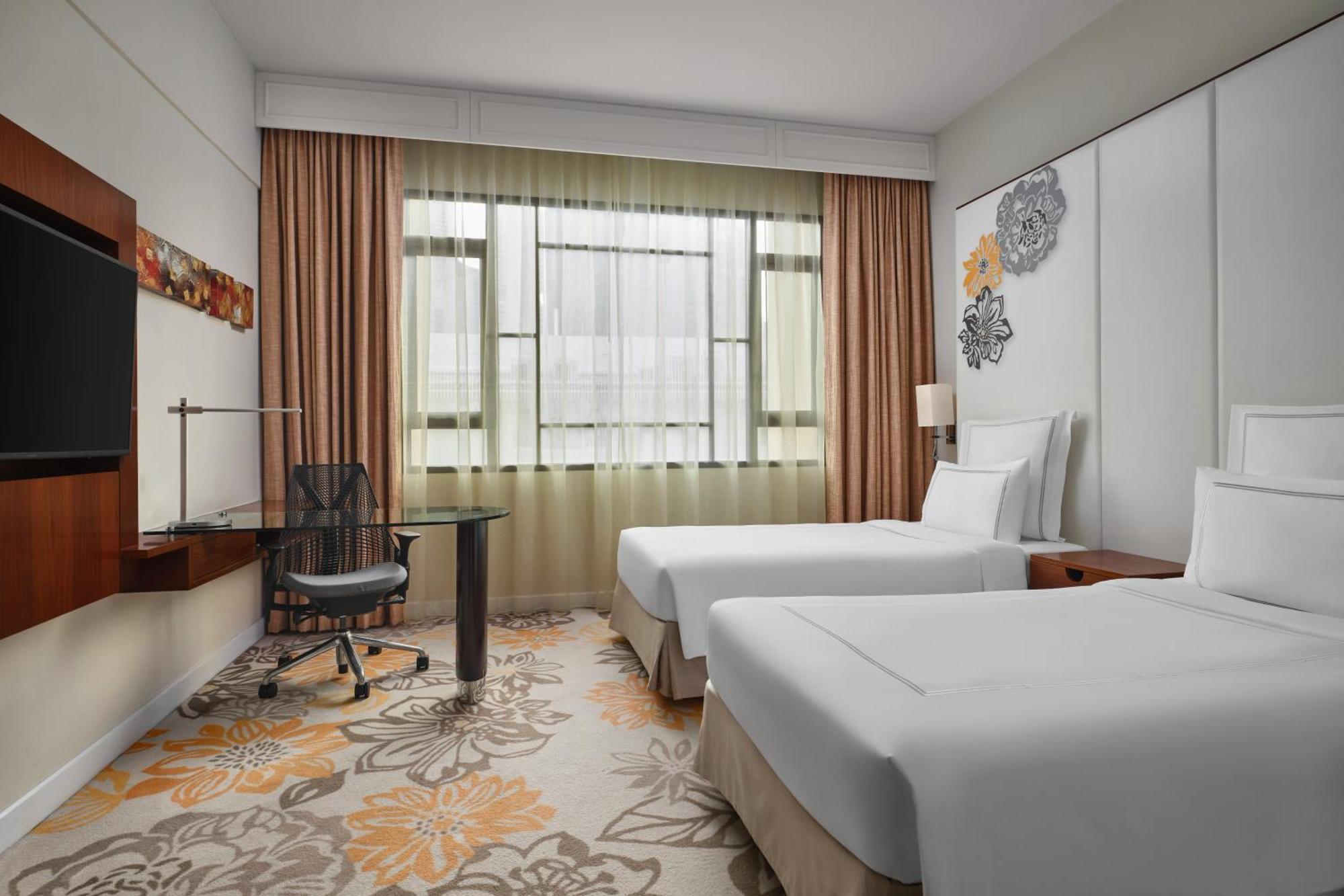 Paradox Singapore Merchant Court At Clarke Quay Exterior photo The photo shows a modern hotel room featuring two twin beds with white bedding. There is a large window with sheer curtains allowing natural light to fill the space. In the corner, there's a stylish desk with an ergonomic chair. The room has a light 